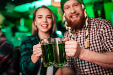 A man in a funny hat and a girl are drinking beer together.