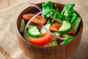 Close up green salad with tomato, onion, rustic style.