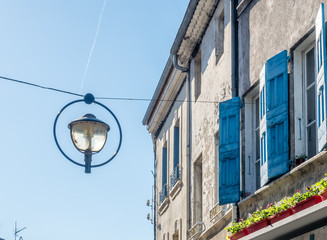 Night lantern hang over street in old classic buildings in countryside of France, under clear blue sky in daylight time