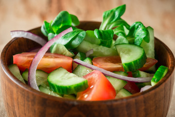 Close up green salad with tomato, onion, rustic style.