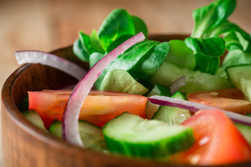 Close up green salad with tomato, onion, rustic style.