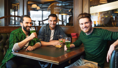 male friends drinking green beer at bar or pub