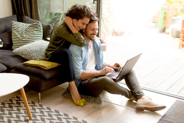 Young couple sitting on floor and using notebook.