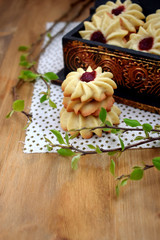 Shortbread cookies with jam on a cloth surrounded by branches 