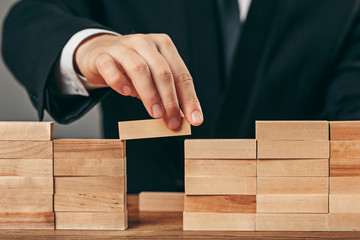 Man and wooden cubes on table. Management concept