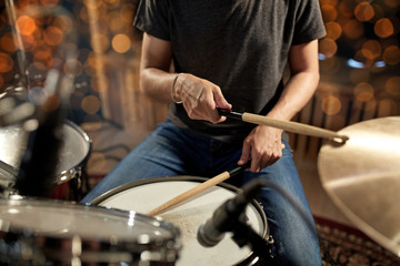 musician playing drum kit at concert over lights