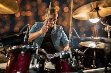 musician playing drum kit at concert over lights