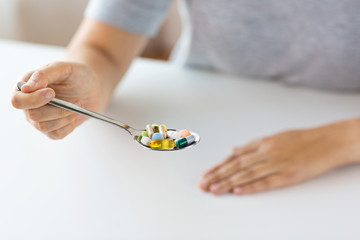 close up of female hand holding spoon with pills
