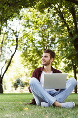 Handsome young man using laptop outdoors