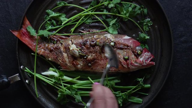 Grilled Whole Red Snapper with Ginger Soy Sauce and Garnish. Served hot in the Frying Pan.