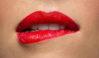 close up of woman with red lipstick biting lip