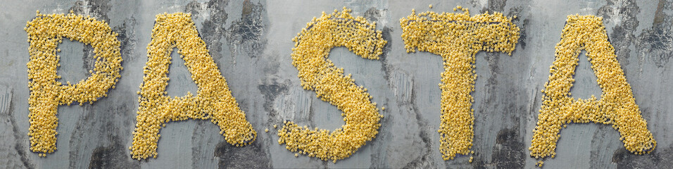 Word pasta created from pasta macaroni on the wooden table in the kitchen