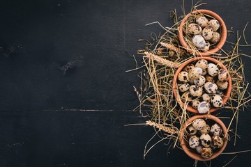 Quail eggs in a wooden bowl. On a wooden background. Top view. Copy space.