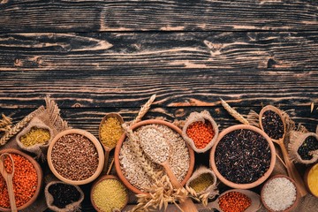 Set of Groats and Grains. Buckwheat, lentils, rice, millet, barley, corn, black rice. On a wooden  background. Top view. Copy space.