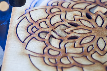 The laser cuts out a tree in the form of a mandala 