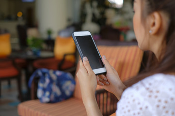 Back side view girl holding a mobile her sit on sofa