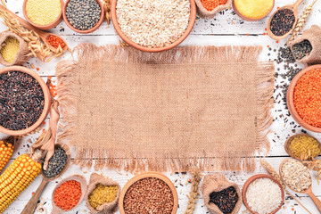 Set of Groats and Grains. Buckwheat, lentils, rice, millet, barley, corn, black rice. On a white wooden background. Top view. Copy space.