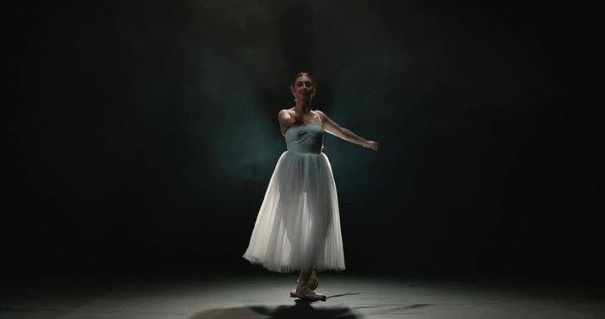 4K video footage beautiful woman ballerina in white tutu on black background, slow motion