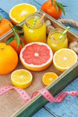 Different fruits and glass with fresh orange juice, wooden background