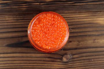 Red caviar in glass jar on wooden table