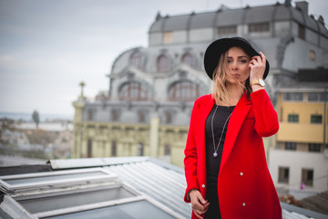 Fototapeta premium Girl in red posing on the roof of old city