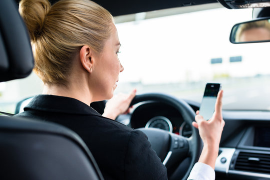 Woman In Suit Texting On Her Phone While Driving By Car