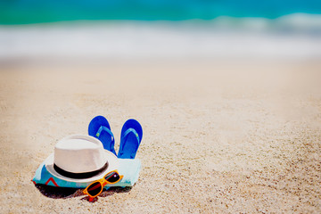 Sandy beach with towel, flip flops   and summer accessories with copy space.   Vacation and travel items. Tropical Holiday Background