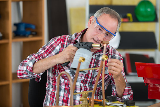 skilled tradesman is soldering a copper pipe
