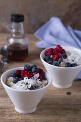 Healthful breakfast  oatmeal with fresh berries, coconut flakes and maple syrup