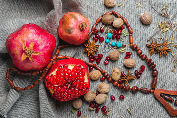 Juicy aromatic pomegranate on the table with a decor of national ornaments.