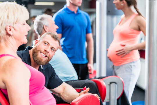 Senior woman with trainer in group with pregnant woman working out at the gym