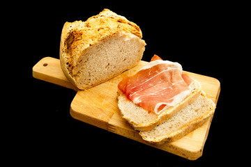 Sliced Bread with raw ham on cutting table, black background