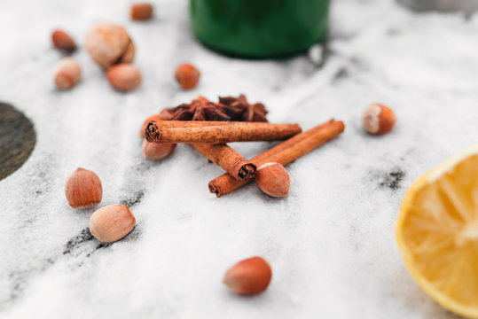 cinnamon, hazelnuts, cardamom on snow-covered glass in the forest