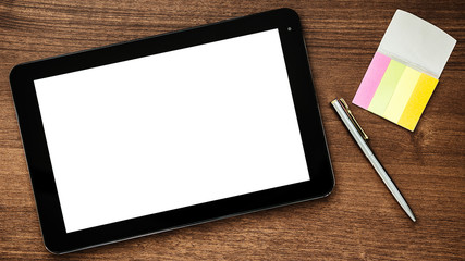 Digital tablet computer, papers and pen on a wooden table. Top view.