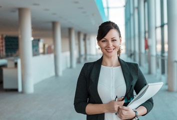 Portrait of a successful business woman holding documents and smiling.