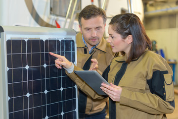Workers with tablet looking at solar panel
