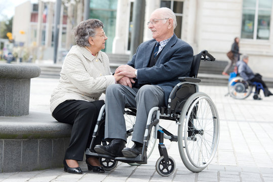 senior on wheelchair with loving wife next to him
