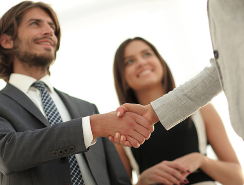 Businesspeople  shaking hands against room with large window loo