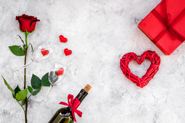 Celebrate Valentine's day. Wine, glasses, red rose, heart sign, gift box on grey background top view copy space