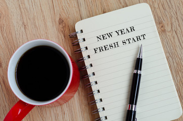 New Year Concept - New year, fresh start text on notepad with pen and a cup of coffee.