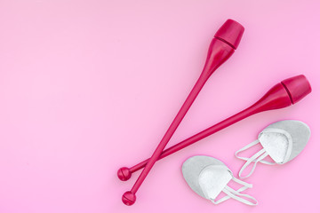 Equipment for rhythmic gymnastics. Clubs and gymnastics shoes on pink background top view on pink background top view copy space