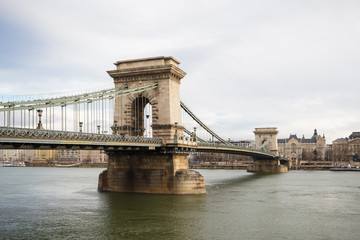 Obraz premium Chain Bridge with Danube river flowing under it as seen from riverside od Danube river in Budapest, Hungary.