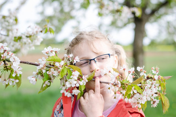 girl in glasses and blossoming twig of tree