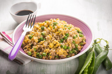 barley risotto woth green peas scramble eggs and soy sauce,  selective focus