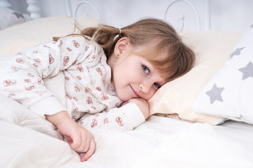 Portrait of a little beautiful girl in bed in the early morning