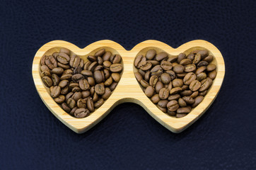 coffee beans in the heart shape wooden plate on black leather