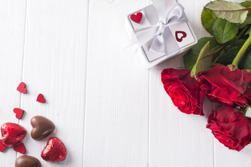 Valentines concept with bouquet of roses and wrapped gift on wooden table