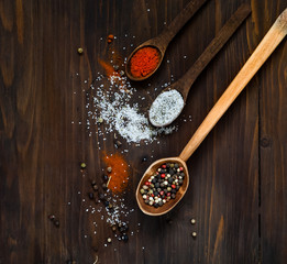 Wooden spoon and ingredients on a dark background. Concept of spicy food, top view, empty space for text.