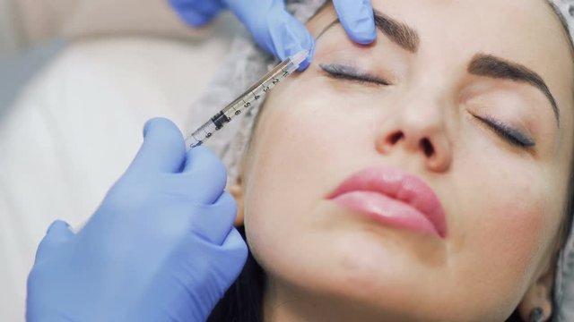 Woman lifts her eyelid and makes cosmetological procedure with botox