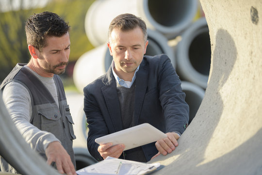 checking the paperwork for an order of concrete pipes